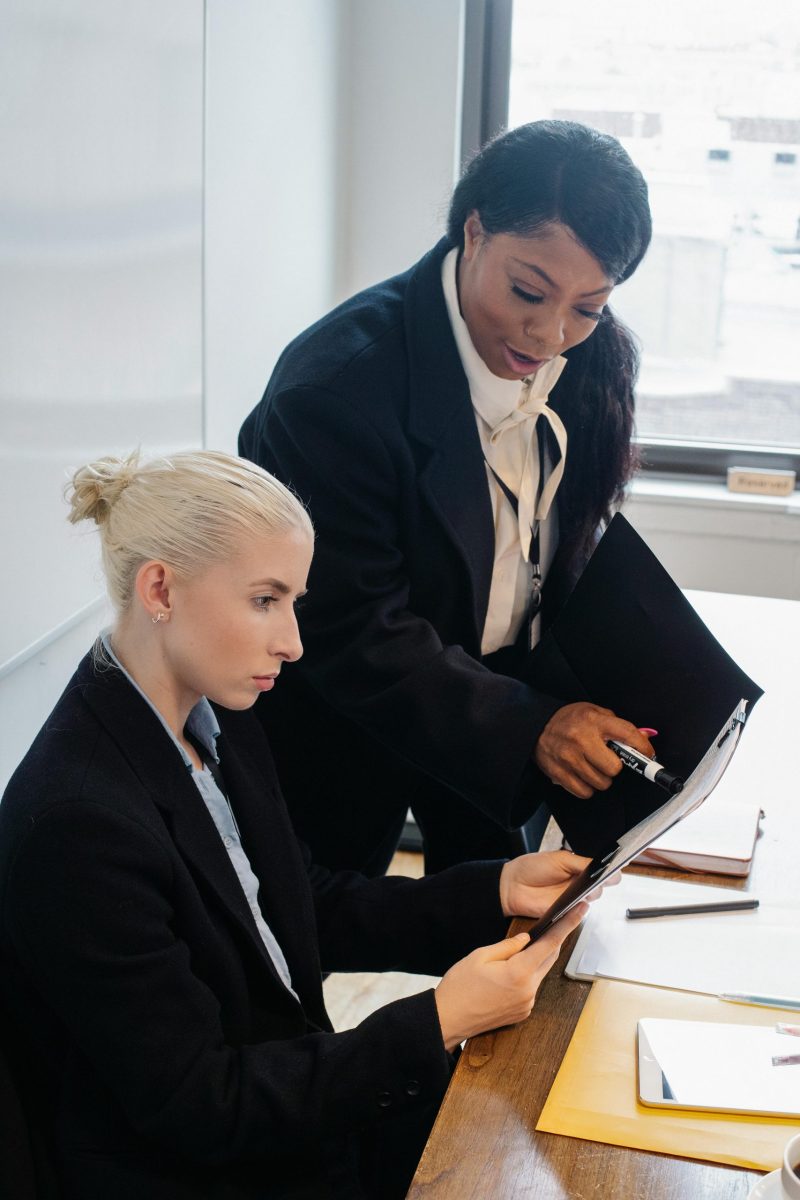 Diverse women in formal clothes gathering in modern workspace and discussing business ideas while working together